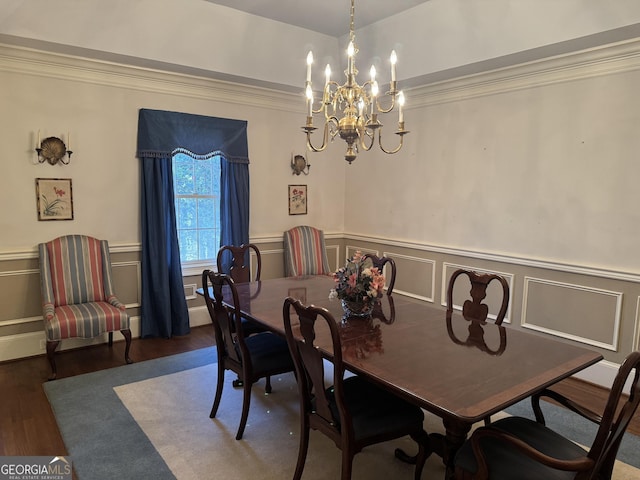 dining space featuring ornamental molding, a decorative wall, wood finished floors, and wainscoting