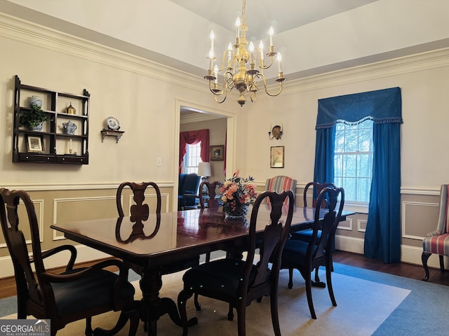 dining space with crown molding, wainscoting, a decorative wall, and wood finished floors