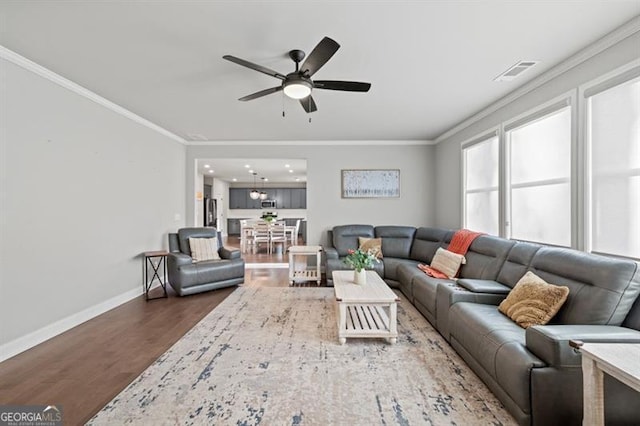 living room featuring visible vents, crown molding, baseboards, and wood finished floors