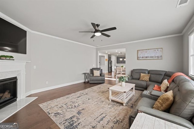 living room featuring ornamental molding, a premium fireplace, wood finished floors, and visible vents