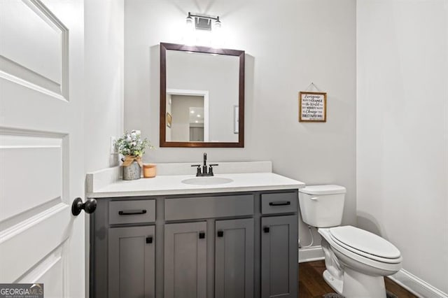 bathroom with baseboards, vanity, toilet, and wood finished floors