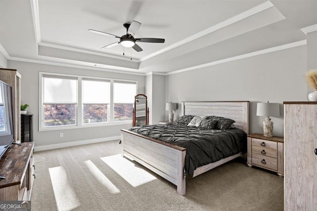 carpeted bedroom featuring baseboards, a raised ceiling, a ceiling fan, and ornamental molding