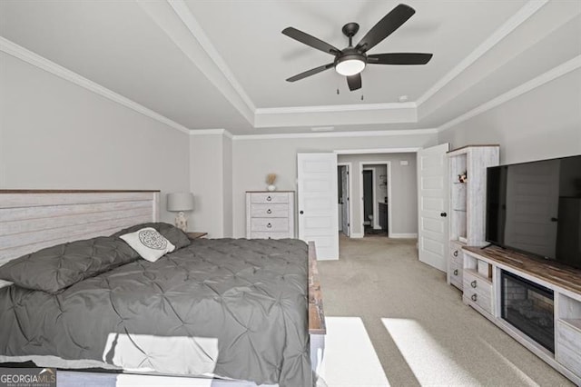 carpeted bedroom with ornamental molding, a raised ceiling, and a ceiling fan