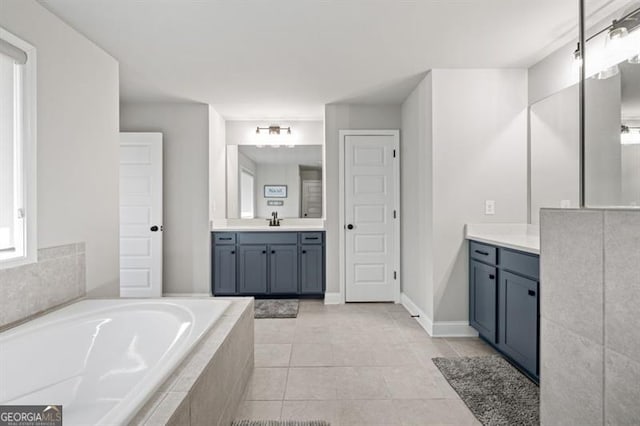 bathroom with tile patterned flooring, vanity, baseboards, and a bath