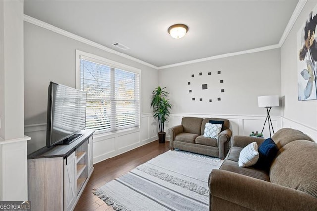 living room featuring dark wood-type flooring, wainscoting, visible vents, and crown molding