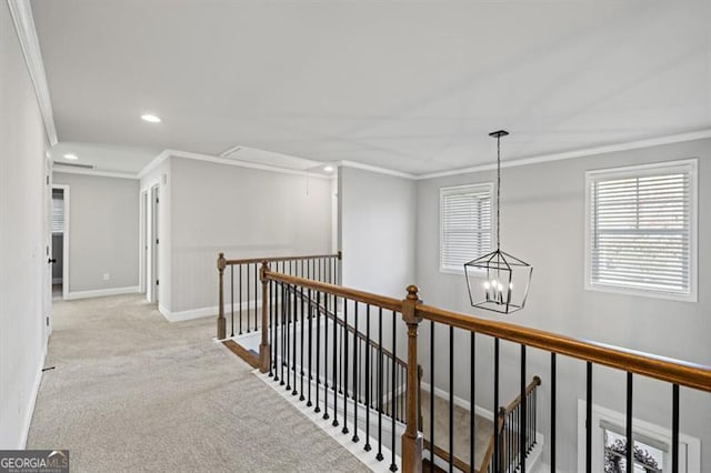 hallway featuring attic access, ornamental molding, carpet flooring, an upstairs landing, and baseboards