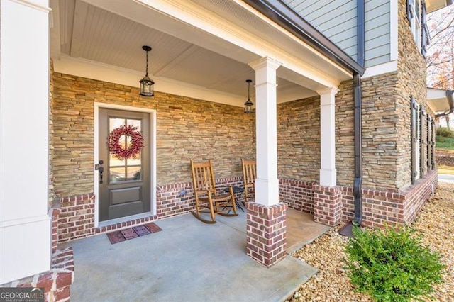 property entrance featuring stone siding, covered porch, and brick siding