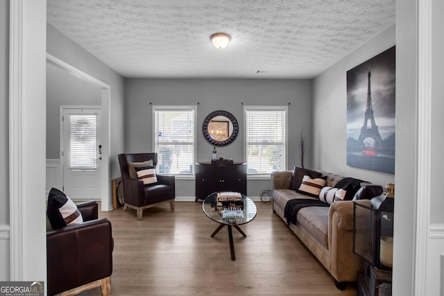 living area with a textured ceiling, visible vents, and wood finished floors