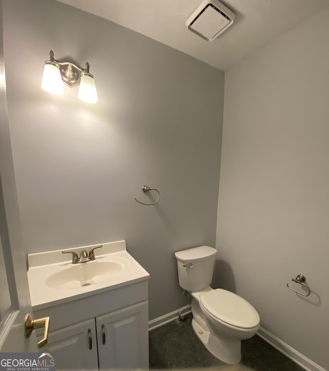 half bath featuring toilet, vanity, visible vents, and baseboards