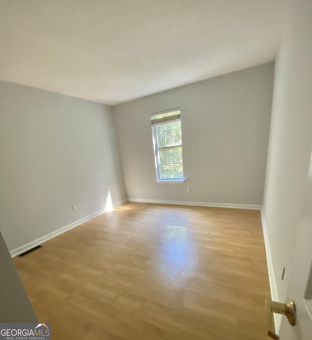 unfurnished room featuring light wood-type flooring, visible vents, and baseboards