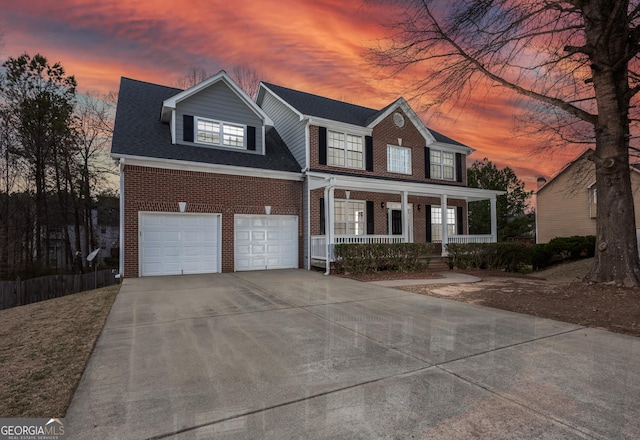 colonial inspired home featuring an attached garage, covered porch, brick siding, a shingled roof, and driveway