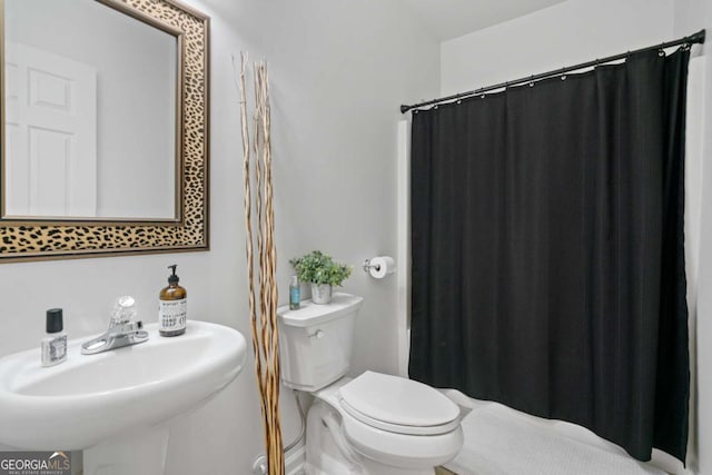 bathroom featuring a shower with curtain, a sink, and toilet