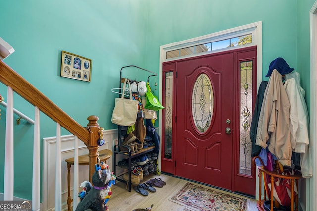 foyer entrance featuring stairs, wainscoting, and wood finished floors