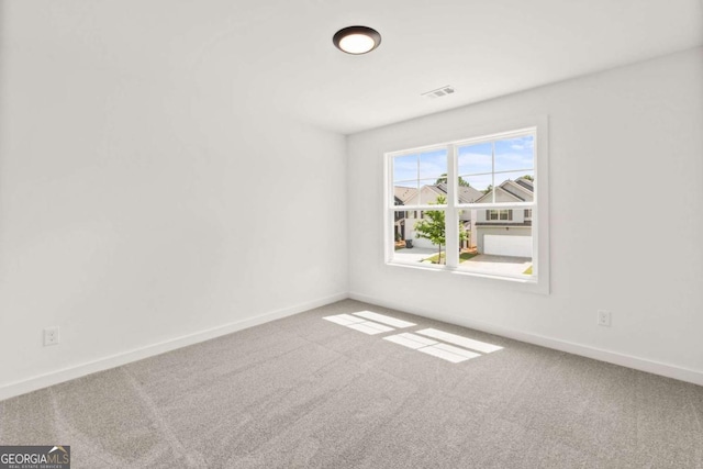 empty room with carpet flooring, visible vents, and baseboards