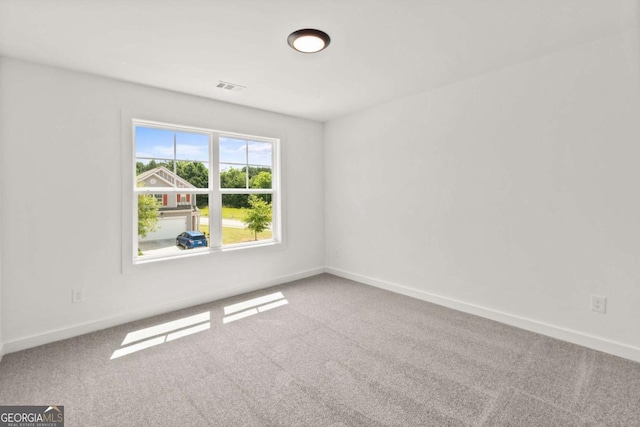 empty room with carpet floors, visible vents, and baseboards