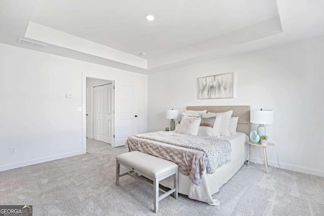 bedroom featuring a tray ceiling, carpet, visible vents, and baseboards