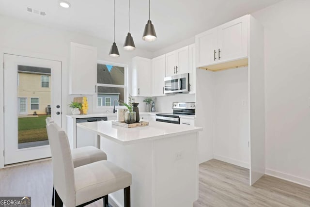 kitchen with a breakfast bar area, visible vents, appliances with stainless steel finishes, white cabinets, and a kitchen island