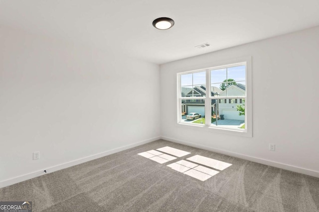 carpeted empty room featuring baseboards and visible vents