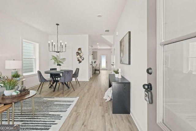 foyer entrance with visible vents, a notable chandelier, light wood-style flooring, and baseboards