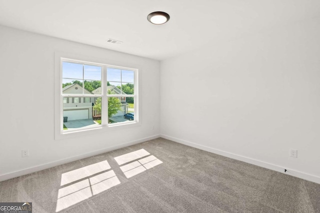 spare room with carpet, visible vents, and baseboards