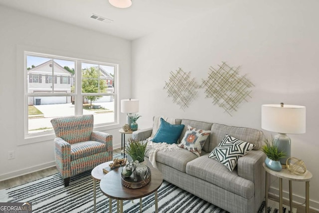 living room with baseboards, visible vents, and wood finished floors