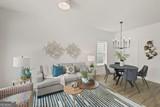 living area featuring a chandelier, wood finished floors, and baseboards