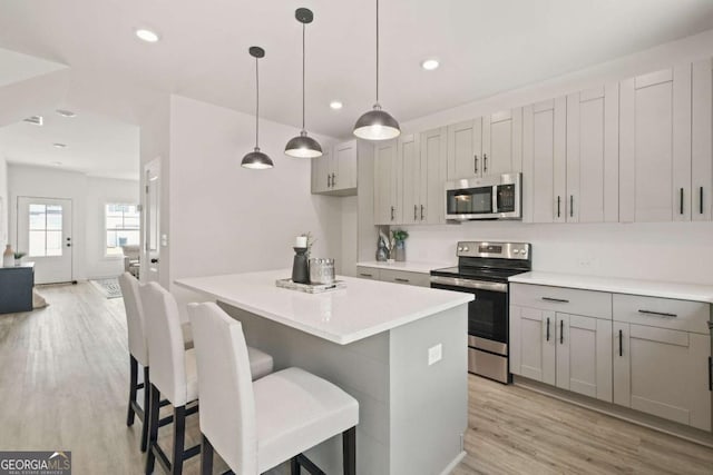 kitchen featuring light wood-type flooring, a kitchen island, stainless steel appliances, and recessed lighting