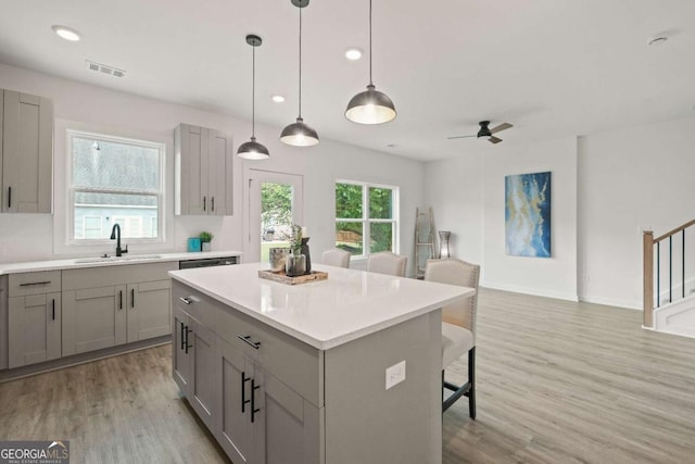 kitchen featuring a center island, gray cabinets, visible vents, a sink, and a kitchen breakfast bar