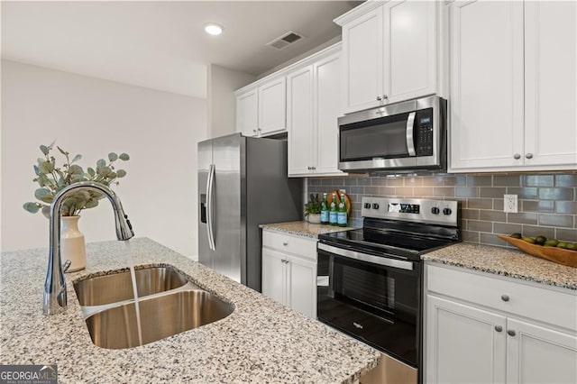 kitchen with stainless steel appliances, a sink, white cabinetry, and decorative backsplash