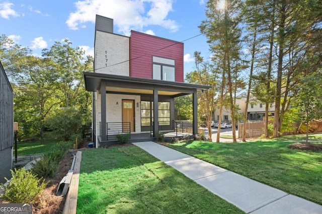 view of front facade with a porch, a front yard, and brick siding