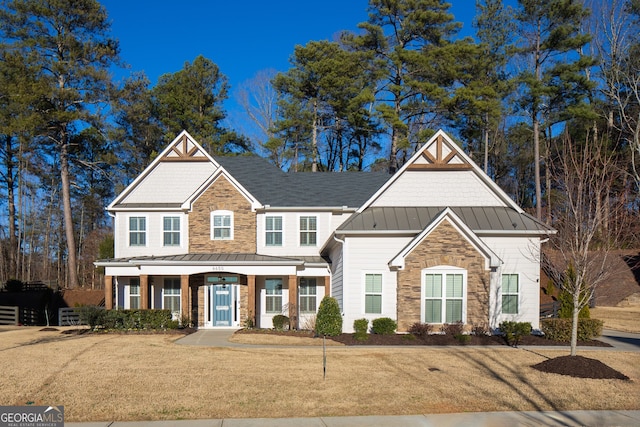 view of front of home featuring metal roof, a front lawn, a standing seam roof, and stone siding