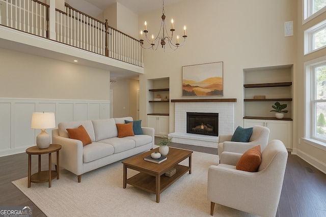 6650 Canyon Cv, Cumming, GA 30028 - living area with built in features, a towering ceiling, wood finished floors, a chandelier, and a fireplace