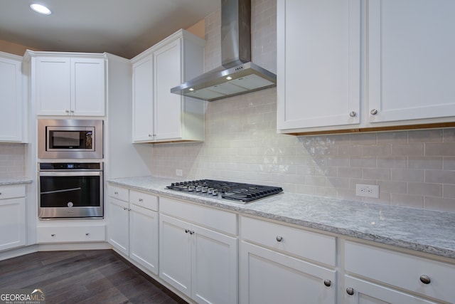 6650 Canyon Cv, Cumming, GA 30028 - kitchen with wall chimney exhaust hood, stainless steel appliances, decorative backsplash, white cabinetry, and recessed lighting
