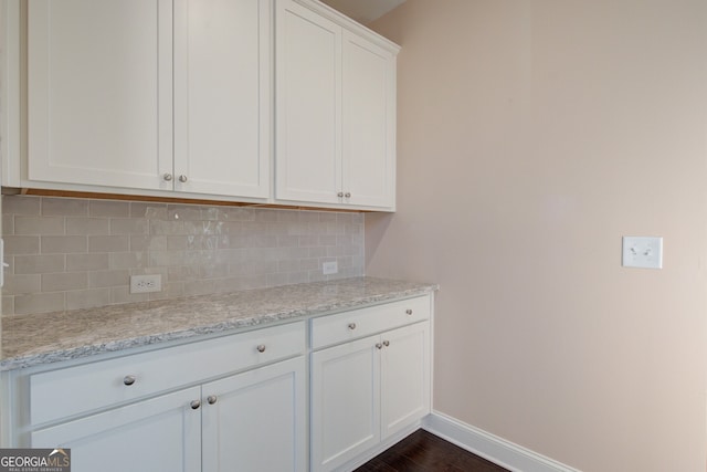 6650 Canyon Cv, Cumming, GA 30028 - kitchen featuring backsplash, baseboards, white cabinetry, light stone counters, and dark wood finished floors