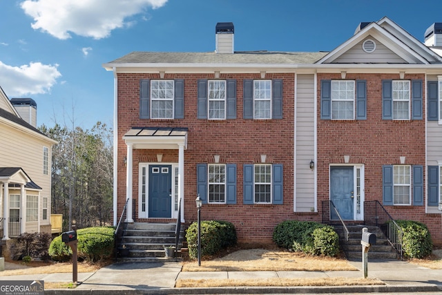 townhome / multi-family property with brick siding and a chimney