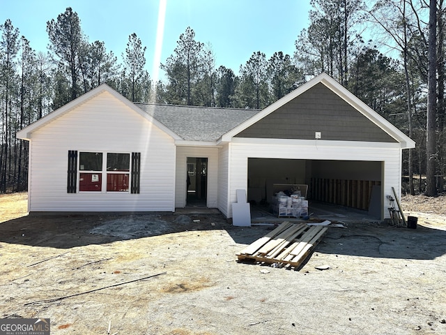 view of front of property with a garage, driveway, and roof with shingles