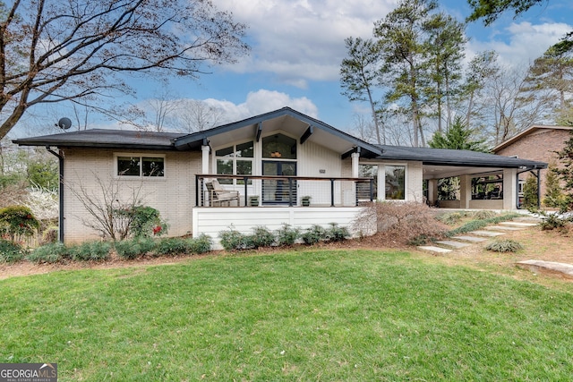 view of front of house featuring a front lawn, a porch, a carport, and brick siding