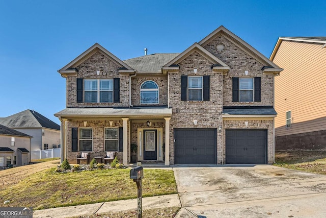 view of front of house featuring brick siding, concrete driveway, an attached garage, covered porch, and a front yard