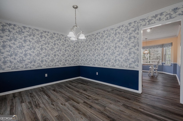 empty room featuring wallpapered walls, baseboards, wood finished floors, an inviting chandelier, and crown molding