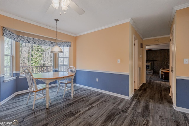 dining space featuring a brick fireplace, baseboards, dark wood finished floors, and crown molding