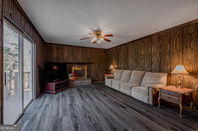 living room with a textured ceiling, wood walls, wood finished floors, and crown molding