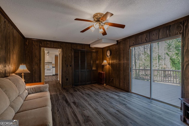 living room with dark wood-style floors, ceiling fan, a textured ceiling, crown molding, and wood walls