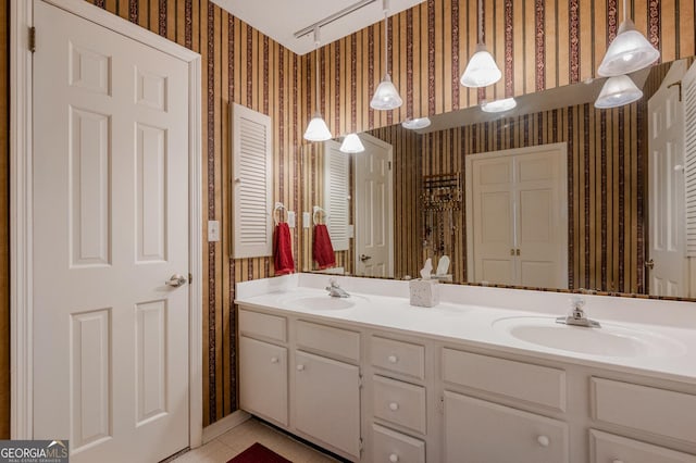 bathroom featuring double vanity, wallpapered walls, a sink, and tile patterned floors