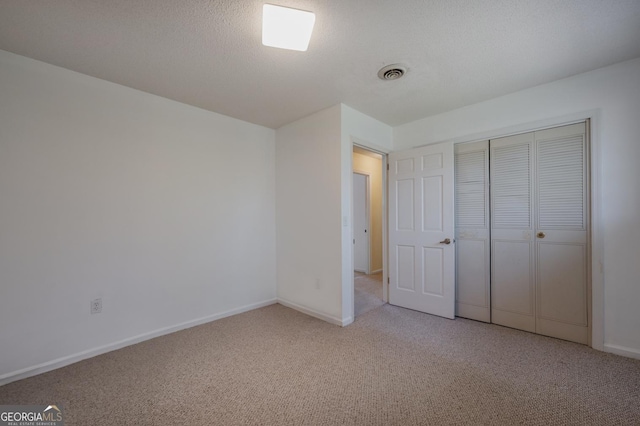 unfurnished bedroom with carpet, a textured ceiling, visible vents, and baseboards