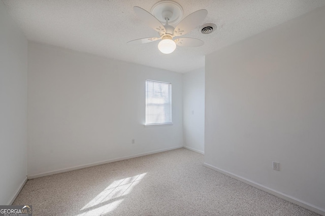 spare room featuring light carpet, visible vents, and a textured ceiling