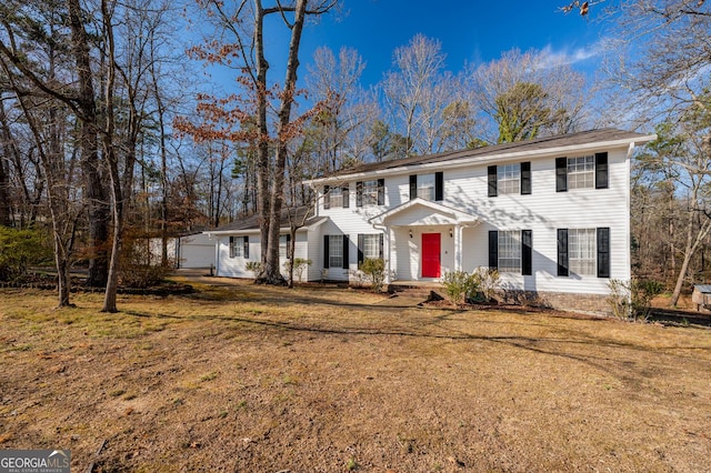 colonial inspired home featuring a garage and a front lawn