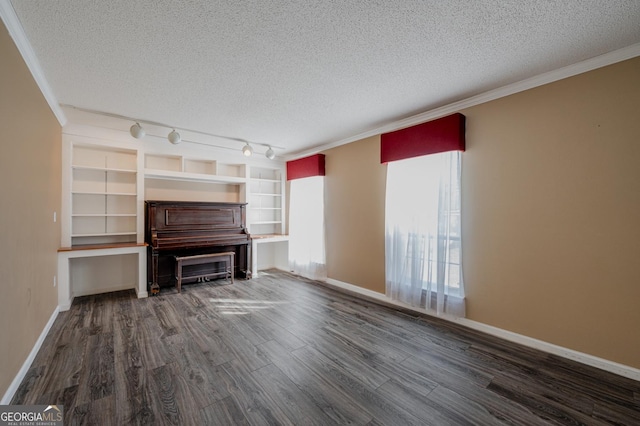 unfurnished living room with a textured ceiling, dark wood-style flooring, baseboards, ornamental molding, and track lighting