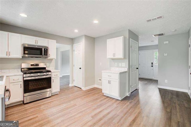 kitchen featuring light wood-style floors, white cabinetry, visible vents, and stainless steel appliances