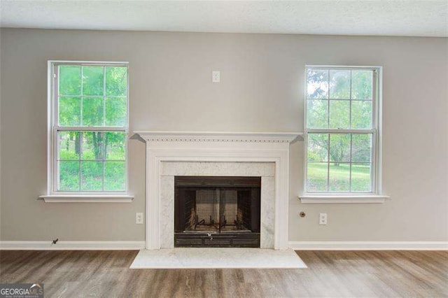 unfurnished living room featuring a textured ceiling, a fireplace, baseboards, and wood finished floors