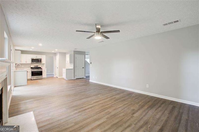 unfurnished living room with a fireplace with flush hearth, baseboards, visible vents, and light wood finished floors